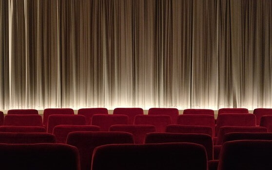 Cual capas o estratos lingüísticos, la imagen tiene cinco filas de butacas con una cortina de cine o teatro con muchos pliegues