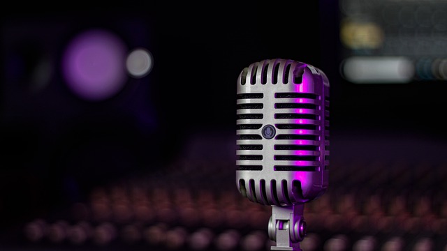 Micrófono con una mesa de mezclas de fondon típica de estudios de grabación de música o doblaje