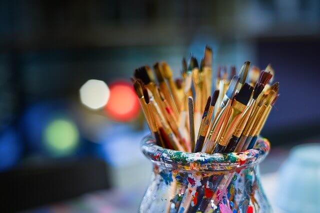 Pinceles sobre boto con restos de colores de pintura para simbolizar los diferentes idiomas y dialectos cuando se busca aprender un acento